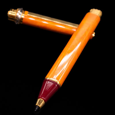 Cartier Vendome Oval Orange Fineliner Pen - Preowned laying across its own cap, crossed, with a focus on the tip.