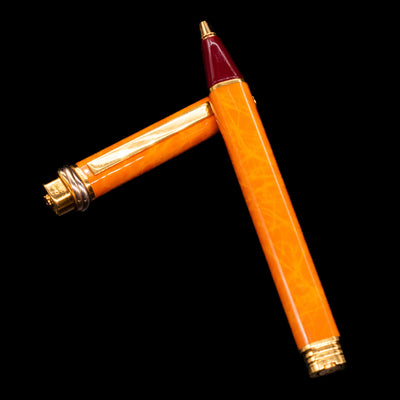 Cartier Vendome Oval Orange Fineliner Pen - Preowned laying on top of its cap in a crossed position showing full view of the entire uncapped pen.