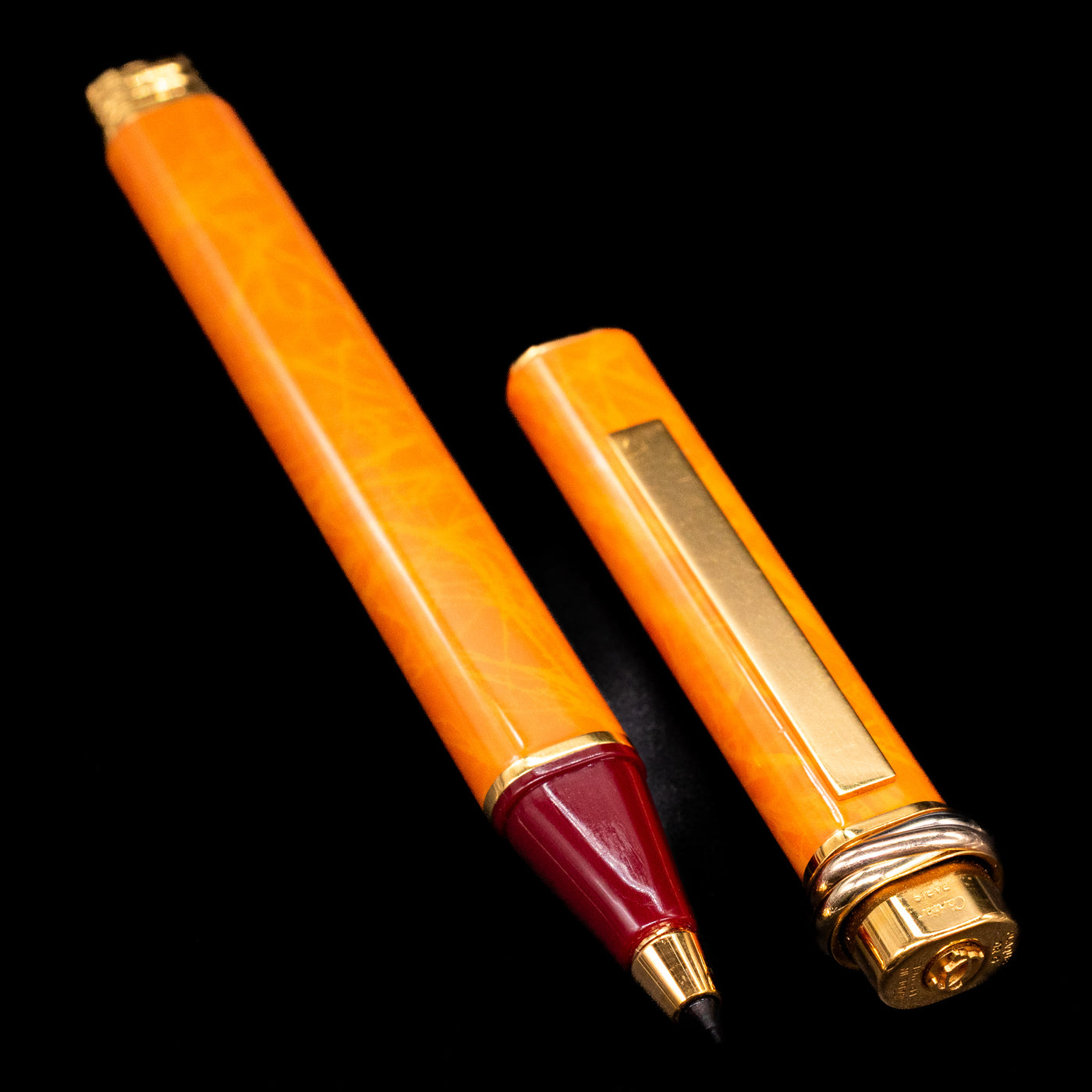 A full view of the Cartier Vendome Oval Orange Fineliner Pen - Preowned uncapped, with its cap laying next to the pen. 