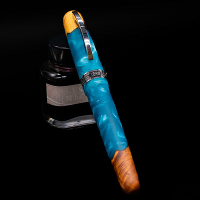 Conklin 1898 Fountain Pen - Spectra Fusion Blue capped, leaning against an ink bottle. 