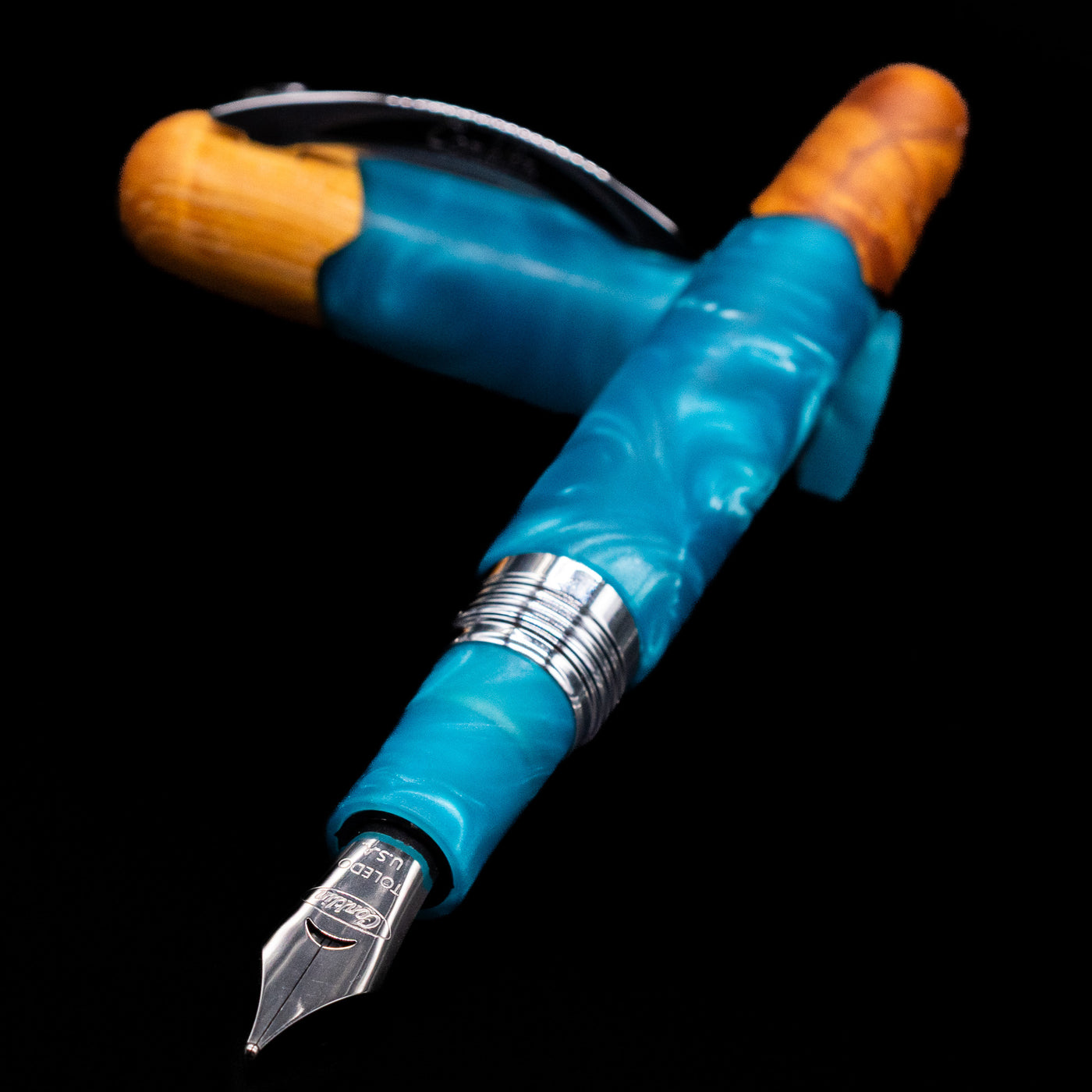 Conklin 1898 Fountain Pen - Spectra Fusion Blue laying across its own cap, crossed, with a focus on the nib.