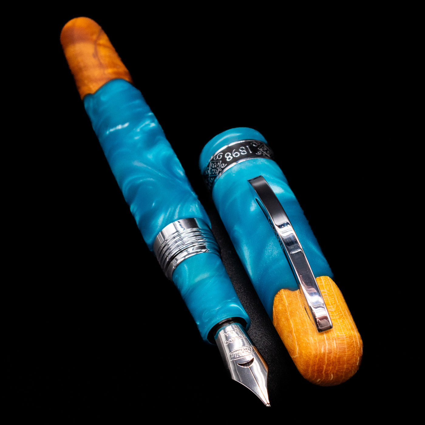  A full view of the Conklin 1898 Fountain Pen - Spectra Fusion Blue uncapped, with its cap laying next to the pen. 