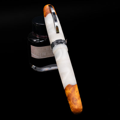 Conklin 1898 Fountain Pen - Spectra Fusion White capped, leaning against an ink bottle. 