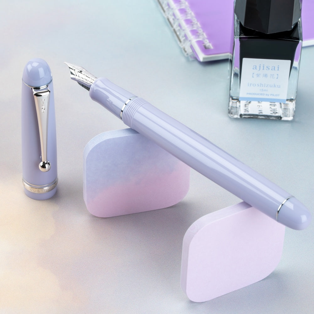 Purple pen set with pen, cap, and ink bottle on a light background