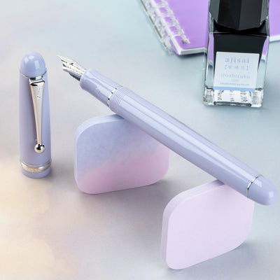 Purple pen set with pen, cap, and ink bottle on a light background