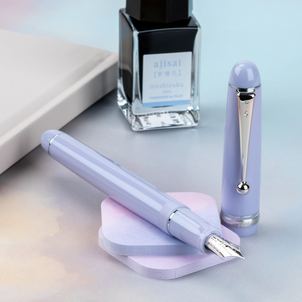 Purple Pilot fountain pen with ink bottle on a light blue background