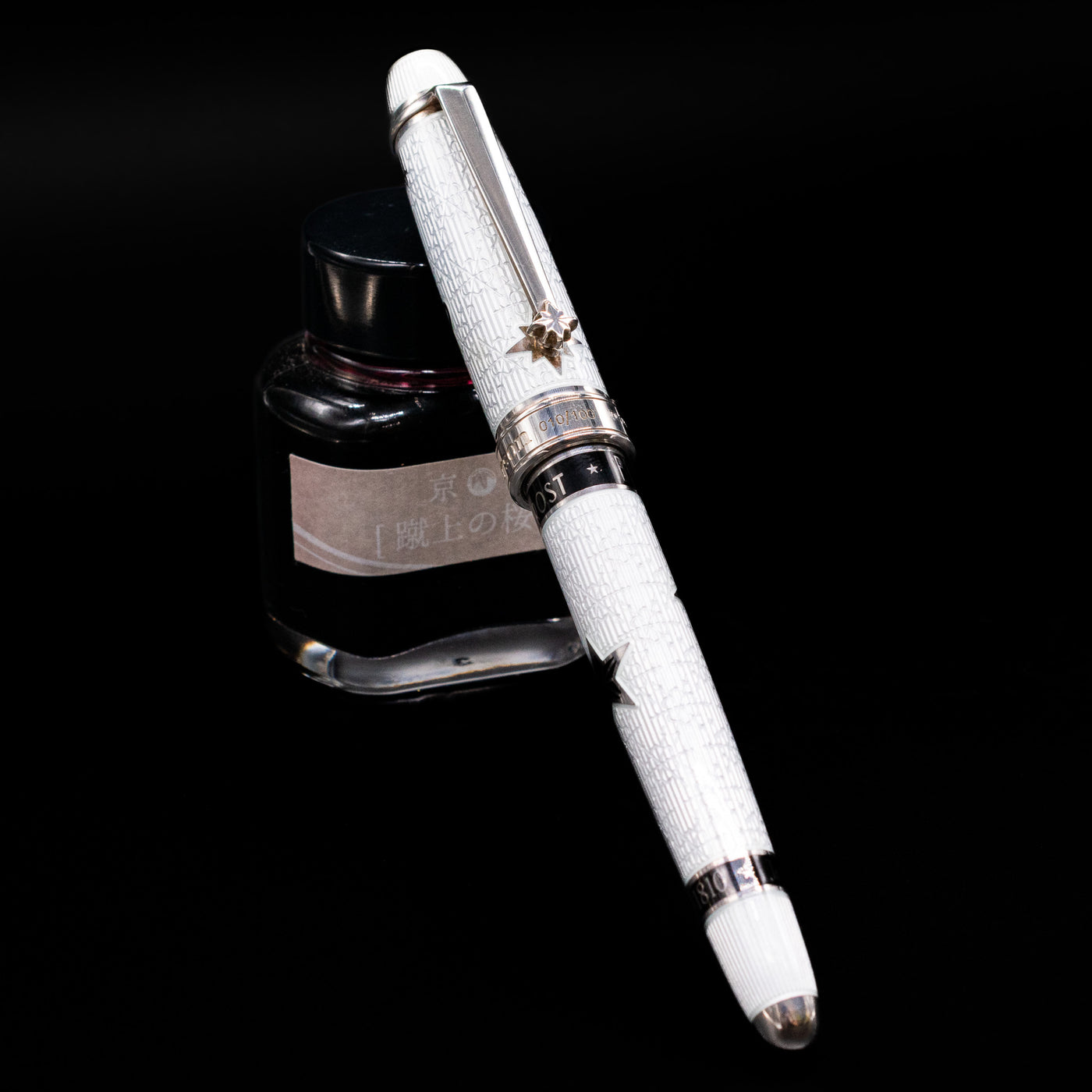 David Oscarson Black Star & Frost Fountain Pen capped, leaning against an ink bottle. 