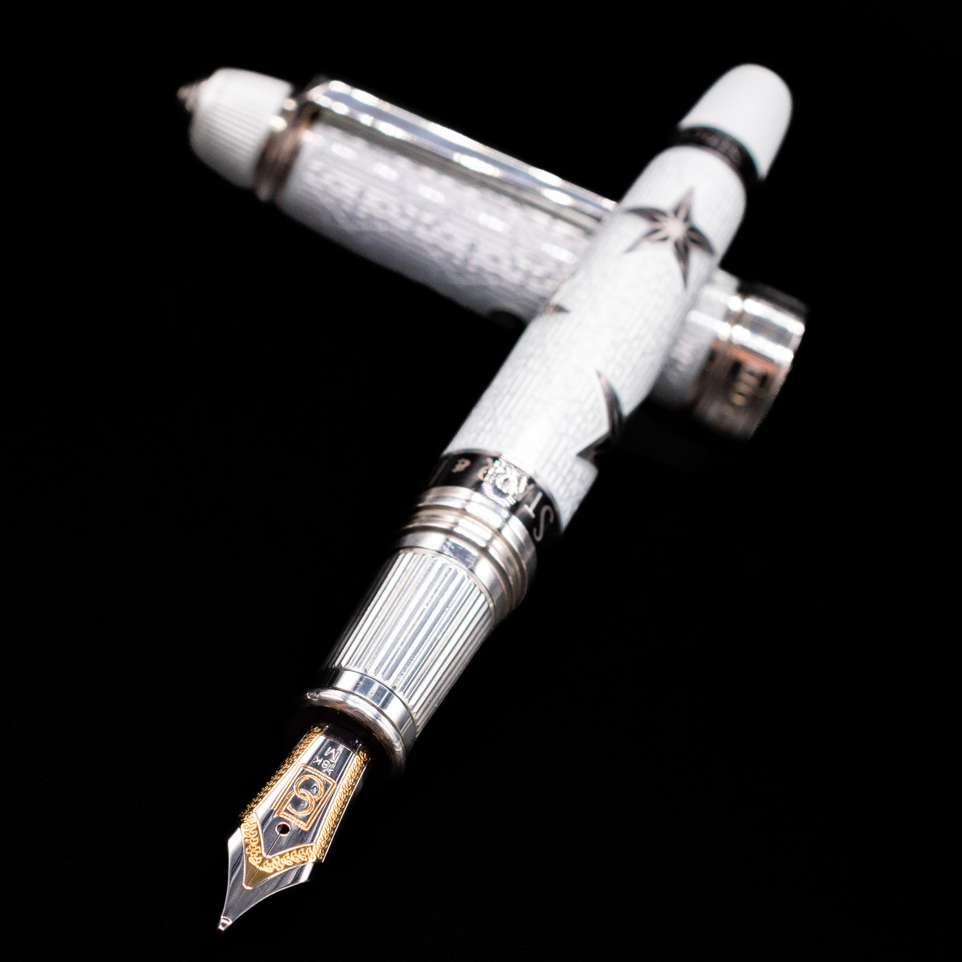 David Oscarson Black Star & Frost Fountain Pen laying across its own cap, crossed, with a focus on the nib.