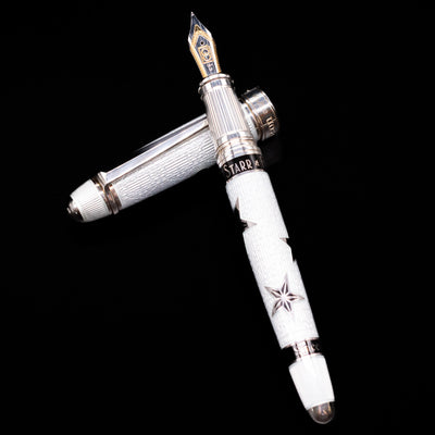 David Oscarson Black Star & Frost Fountain Pen laying on top of its cap in a crossed position showing full view of the entire uncapped pen.