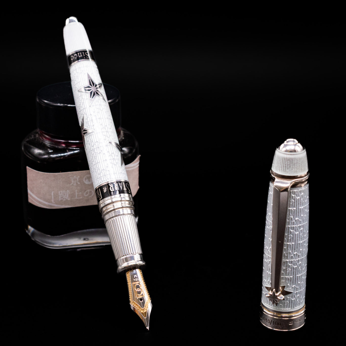 David Oscarson Black Star & Frost Fountain Pen leaning on an ink bottle uncapped showcasing the detailing on the nib.