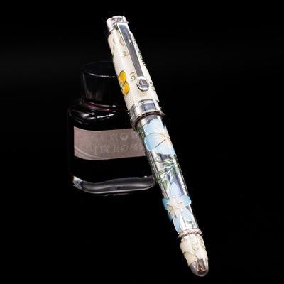 David Oscarson Carl Linnaeus Fountain Pen - White capped, leaning against an ink bottle. 