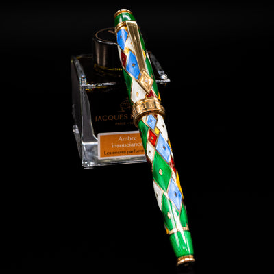 David Oscarson Harlequin Fountain Pen - Emerald Green capped, leaning against an ink bottle. 