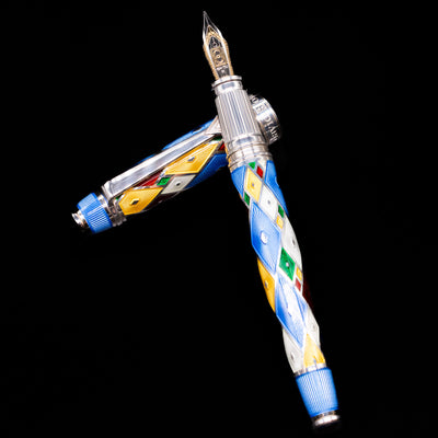 David Oscarson Harlequin Fountain Pen - Sapphire Blue laying on top of its cap in a crossed position showing full view of the entire uncapped pen.