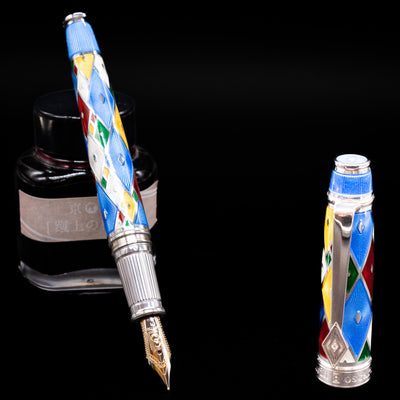 David Oscarson Harlequin Fountain Pen - Sapphire Blue leaning on an ink bottle uncapped showcasing the detailing on the nib.
