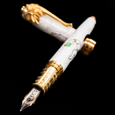 David Oscarson Lord Ganesha Fountain Pen - White laying across its own cap, crossed, with a focus on the nib.