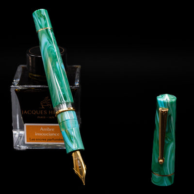 Delta Duna Fountain Pen - Vortex leaning on an ink bottle uncapped showcasing the detailing on the nib.