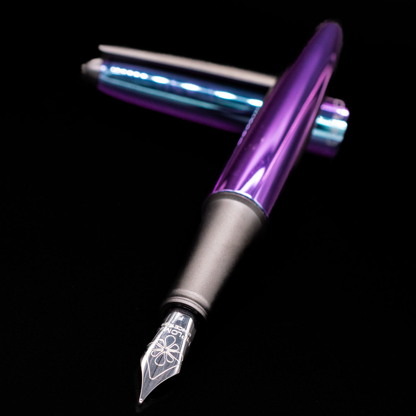Diplomat Aero Fountain Pen - Funky laying across its own cap, crossed, with a focus on the nib.