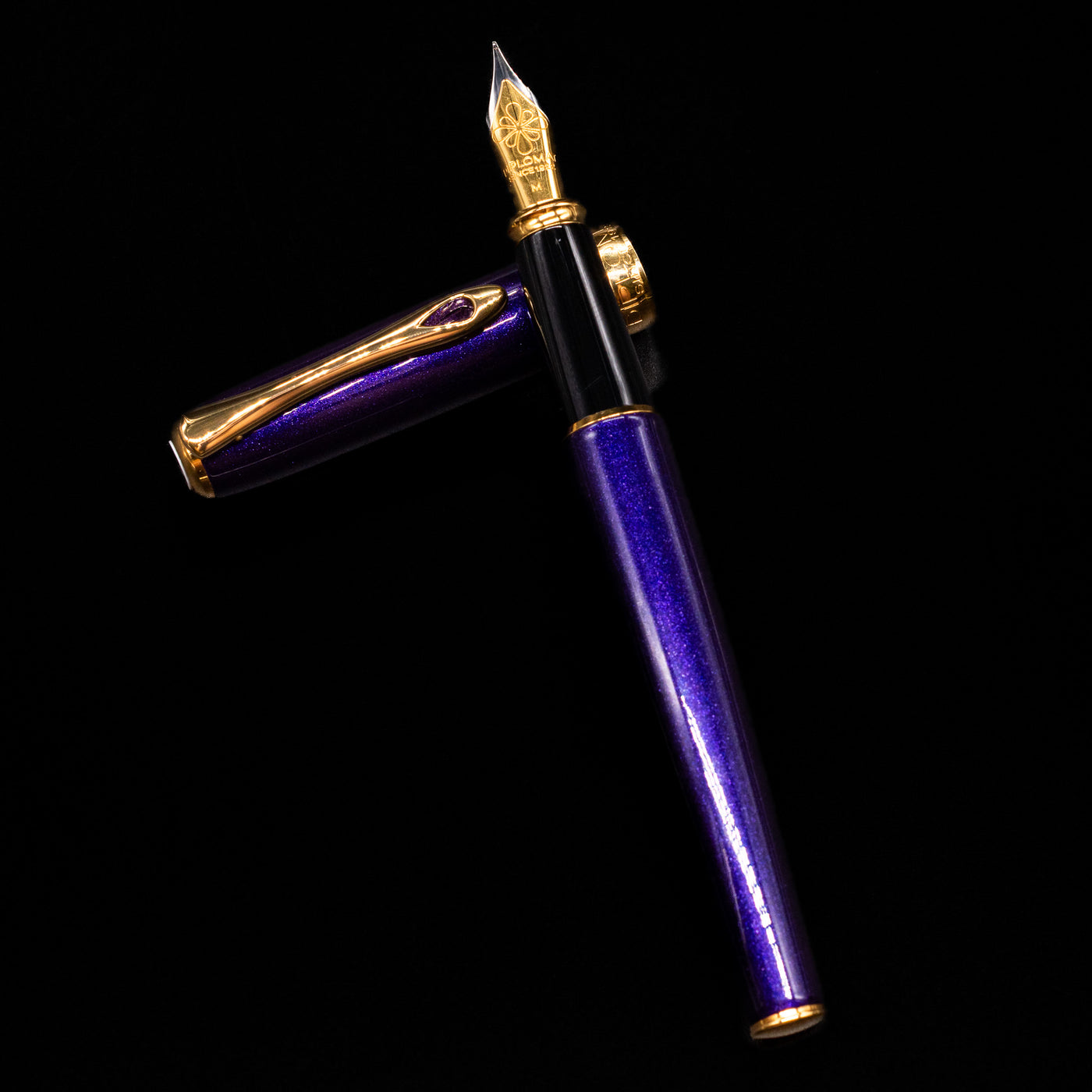 Diplomat Excellence A2 Fountain Pen - Deep Purple laying on top of its cap in a crossed position showing full view of the entire uncapped pen.