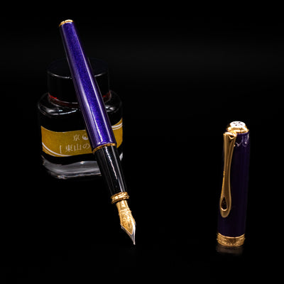 Diplomat Excellence A2 Fountain Pen - Deep Purple leaning on an ink bottle uncapped showcasing the detailing on the nib.