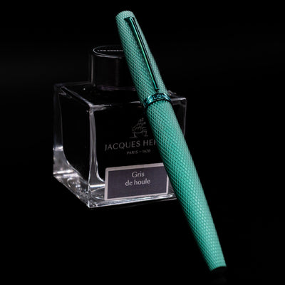 Diplomat Viper Fountain Pen - Green capped, leaning against an ink bottle. 