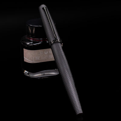 Diplomat Viper Rollerball Pen - Black capped, leaning against an ink bottle. 