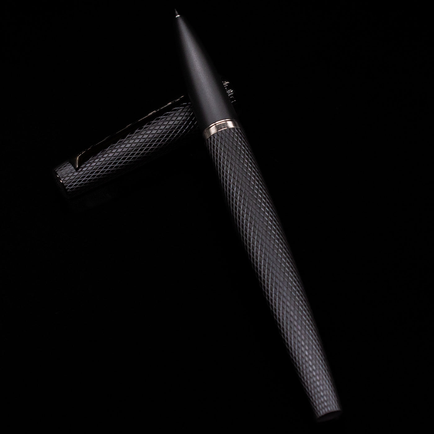 Diplomat Viper Rollerball Pen - Black laying on top of its cap in a crossed position showing full view of the entire uncapped pen.