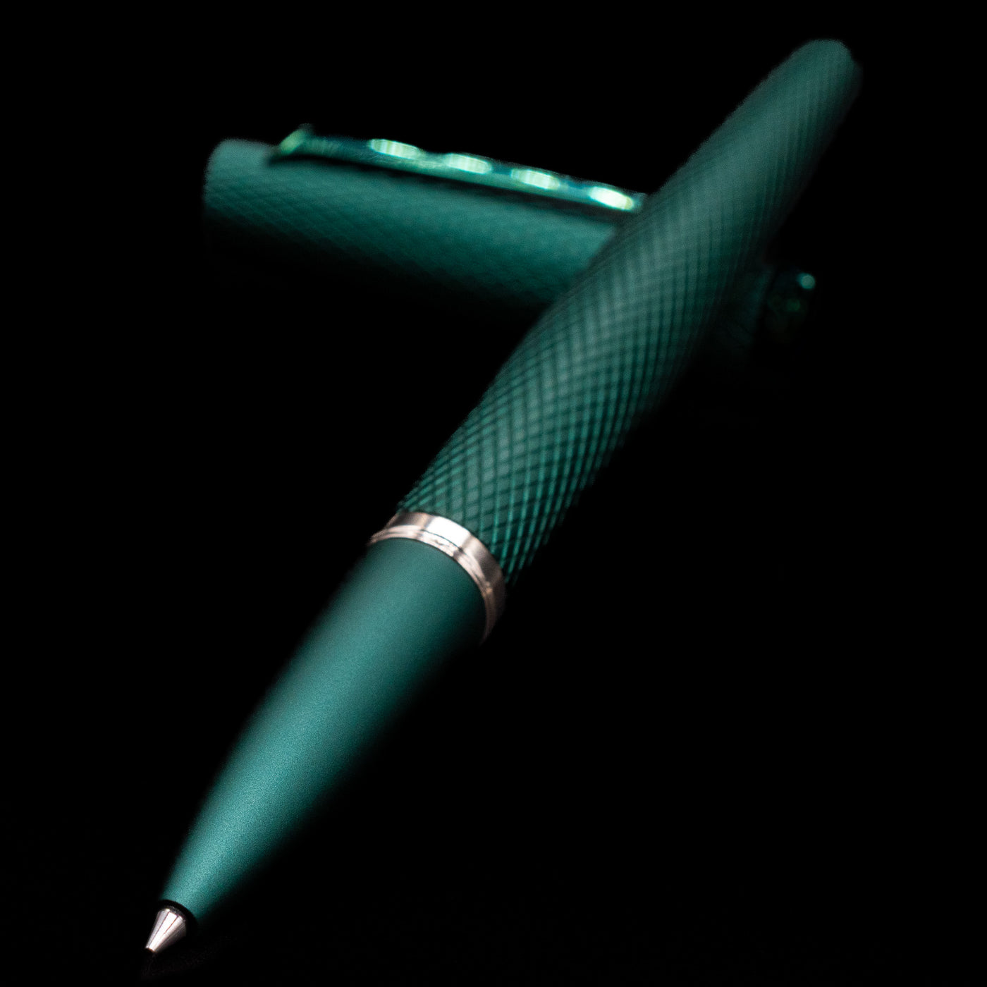 Diplomat Viper Rollerball Pen - Green laying across its own cap, crossed, with a focus on the tip.