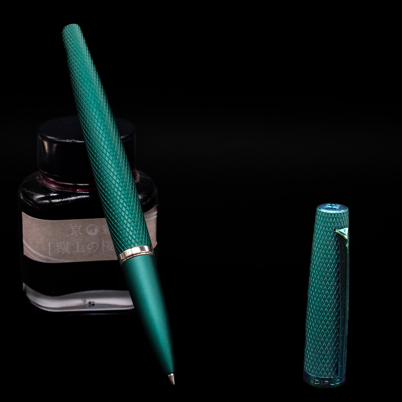 Diplomat Viper Rollerball Pen - Green leaning on an ink bottle uncapped.