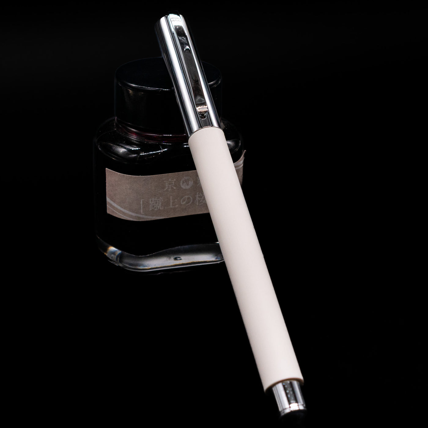 Faber-Castell Ambition Fountain Pen - Cinematic White capped, leaning against an ink bottle. 