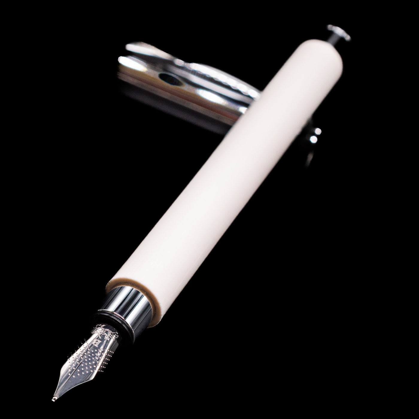 Faber-Castell Ambition Fountain Pen - Cinematic White laying across its own cap, crossed, with a focus on the nib.