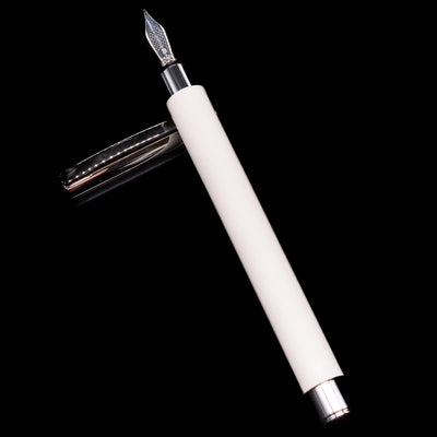 Faber-Castell Ambition Fountain Pen - Cinematic White laying on top of its cap in a crossed position showing full view of the entire uncapped pen.