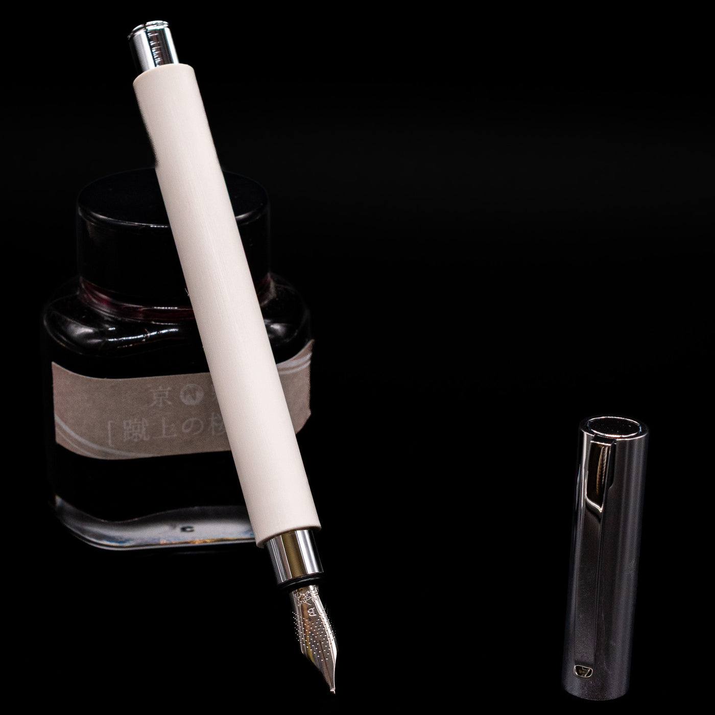 Faber-Castell Ambition Fountain Pen - Cinematic White leaning on an ink bottle uncapped showcasing the detailing on the nib.