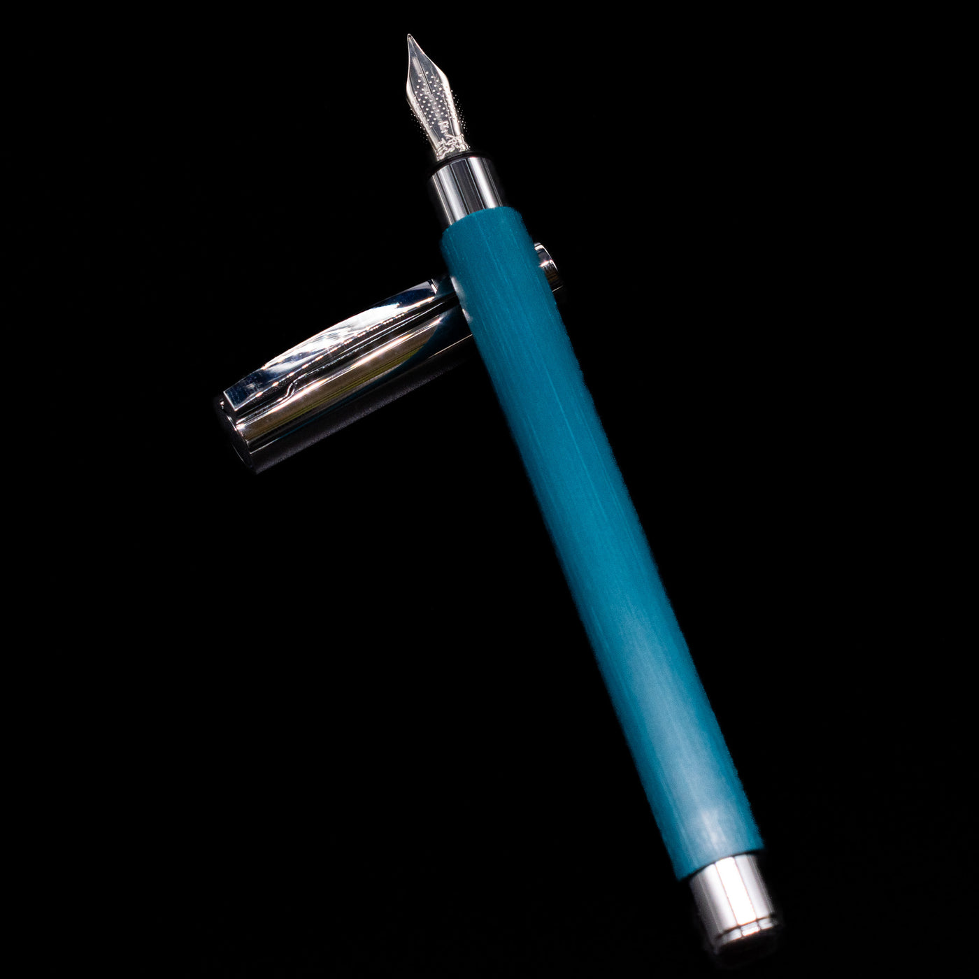 Faber-Castell Ambition Fountain Pen - Soft Teal (Limited Edition) laying on top of its cap in a crossed position showing full view of the entire uncapped pen.