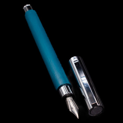  A full view of the Faber-Castell Ambition Fountain Pen - Soft Teal (Limited Edition) uncapped, with its cap laying next to the pen. 