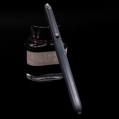 Faber-Castell Avori Ballpoint Pen - Cosmic Flow leaning against an ink bottle.