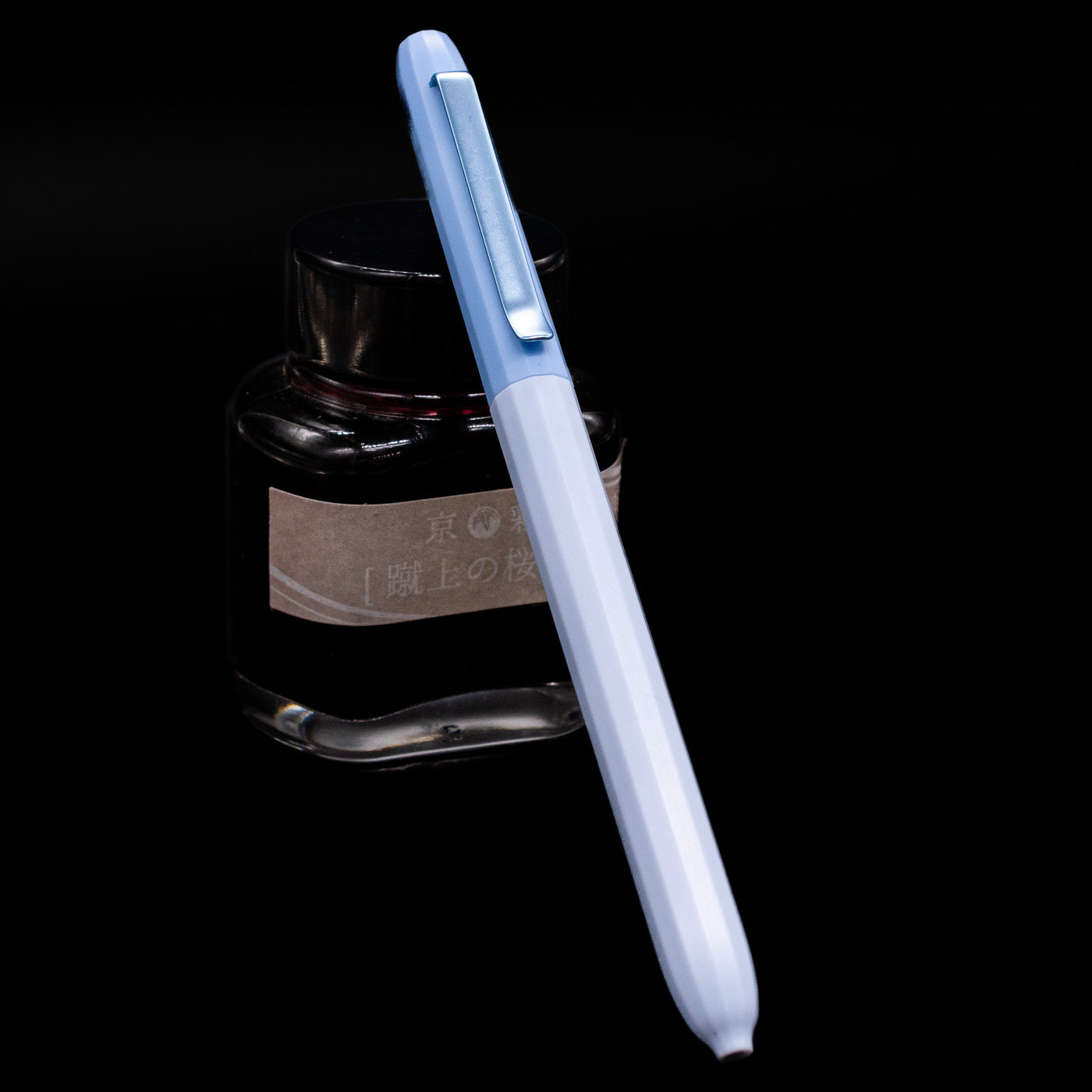 Faber-Castell Avori Ballpoint Pen - Peace of Mind leaning on an ink bottle.