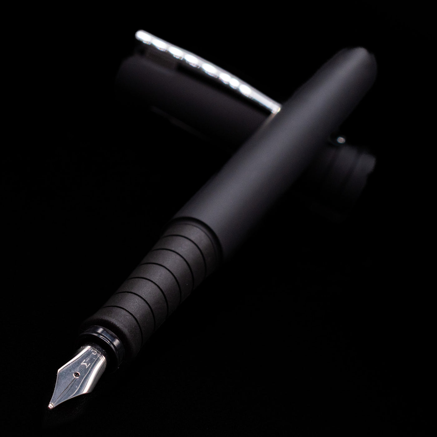 Faber-Castell Poly Fountain Pen - Black laying across its own cap, crossed, with a focus on the nib.