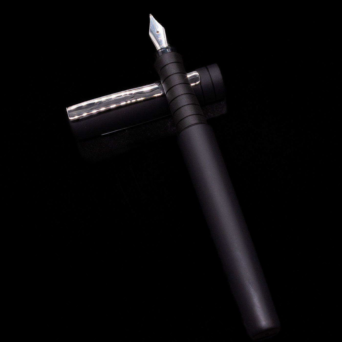 Faber-Castell Poly Fountain Pen - Black laying on top of its cap in a crossed position showing full view of the entire uncapped pen.