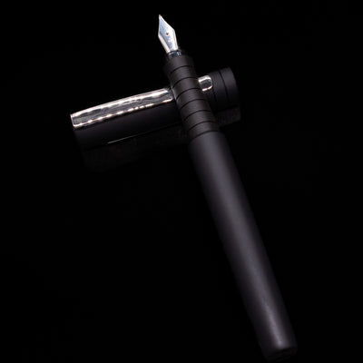 Faber-Castell Poly Fountain Pen - Black laying on top of its cap in a crossed position showing full view of the entire uncapped pen.