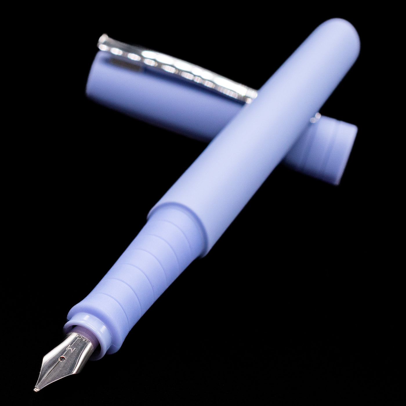 Faber-Castell Poly Fountain Pen - Caribic Blue laying across its own cap, crossed, with a focus on the nib.