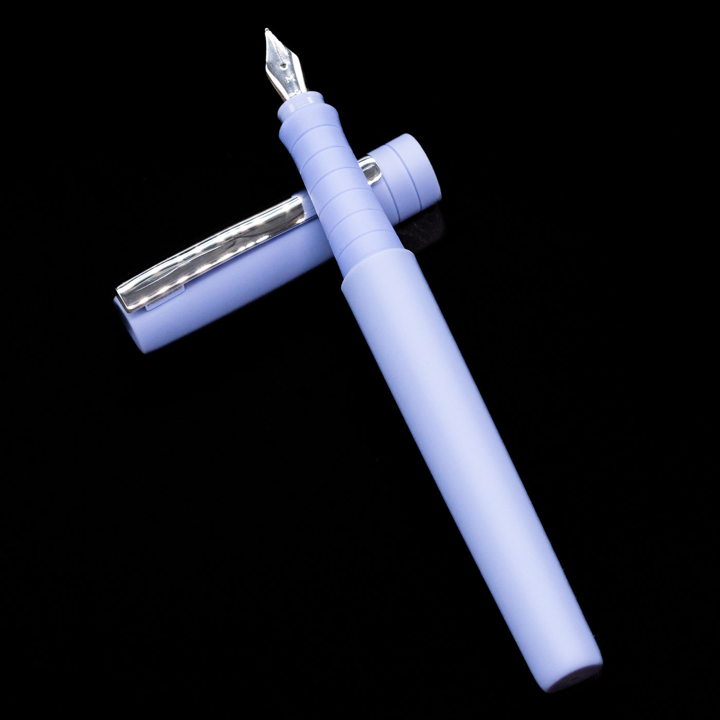 Faber-Castell Poly Fountain Pen - Caribic Blue laying on top of its cap in a crossed position showing full view of the entire uncapped pen.