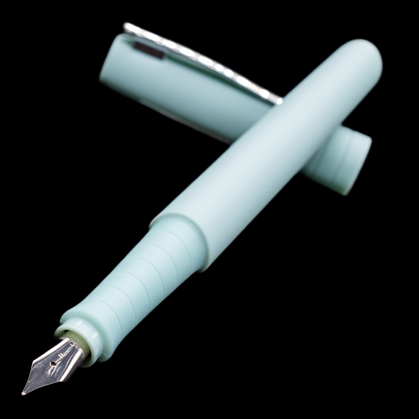 Faber-Castell Poly Fountain Pen - Iris laying across its own cap, crossed, with a focus on the nib.