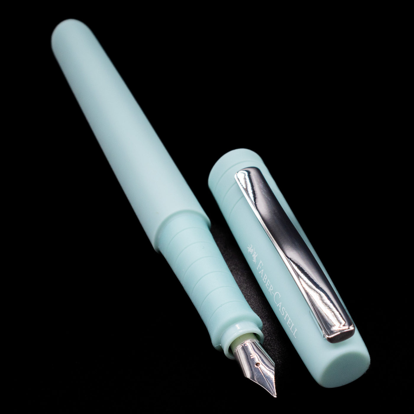 A full view of the Faber-Castell Poly Fountain Pen - Iris uncapped, with its cap laying next to the pen. 