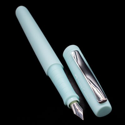 A full view of the Faber-Castell Poly Fountain Pen - Iris uncapped, with its cap laying next to the pen. 