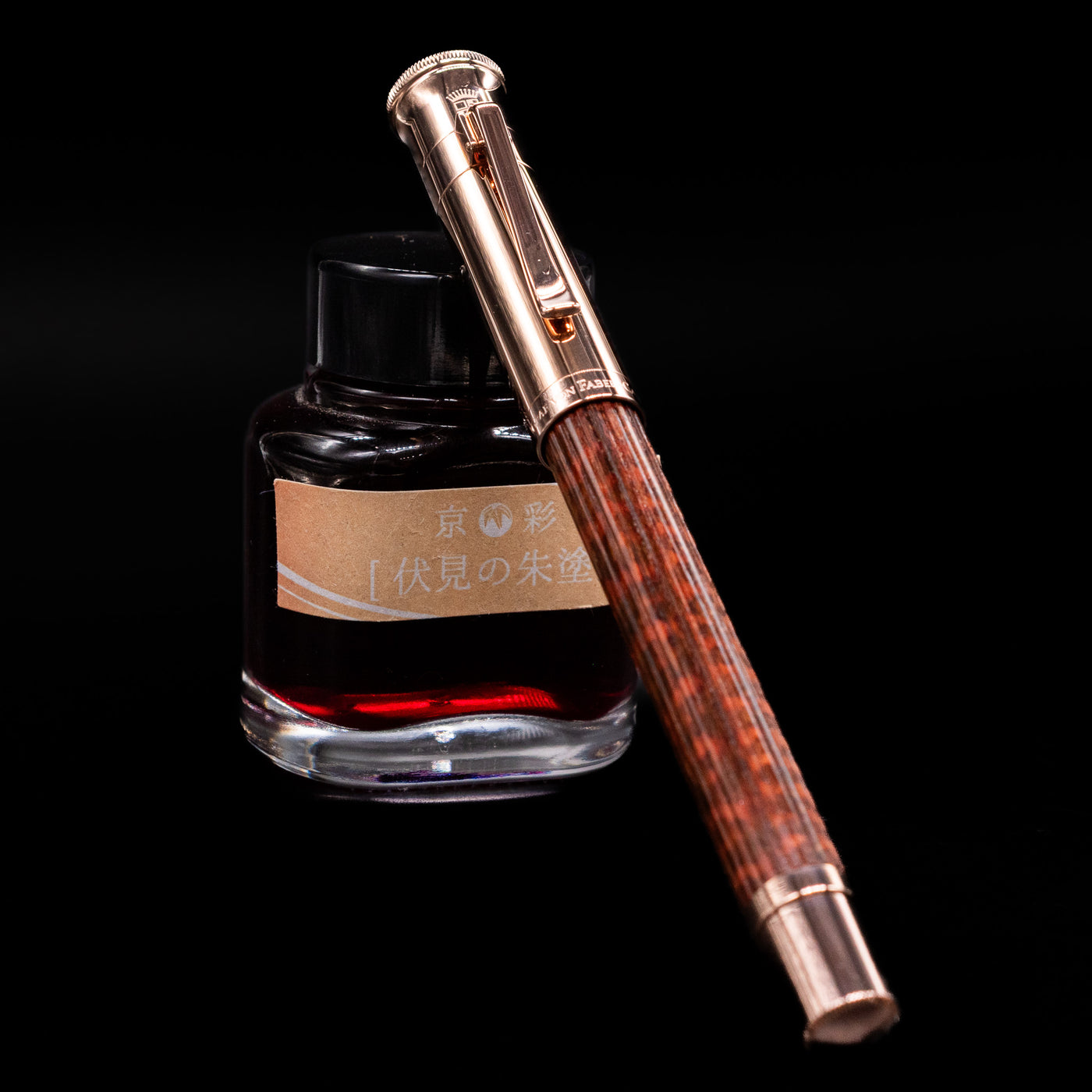Graf von Faber-Castell Classic Limited Edition fountain pen in rich snakewood with rose gold trim, capped, resting diagonally against an ink bottle.