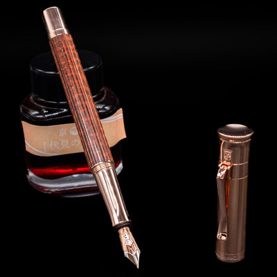 Graf von Faber-Castell Classic Limited Edition fountain pen, uncapped with the nib exposed, leaning on an ink bottle.