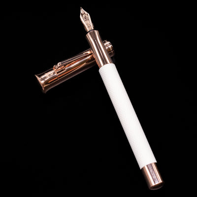 Graf von Faber-Castell Guilloche Fountain Pen - Champagne Blush laying on top of its cap in a crossed position showing full view of the entire uncapped pen.