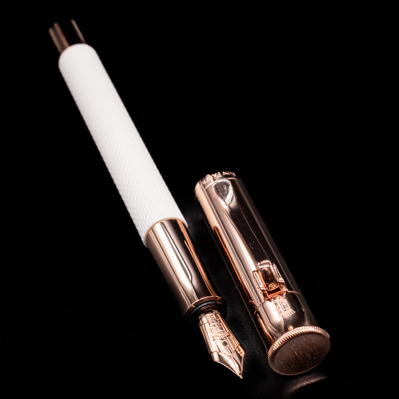 A full view of the Graf von Faber-Castell Guilloche Fountain Pen - Champagne Blush uncapped, with its cap laying next to the pen. 
