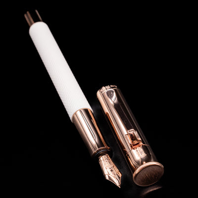 A full view of the Graf von Faber-Castell Guilloche Fountain Pen - Champagne Blush uncapped, with its cap laying next to the pen. 