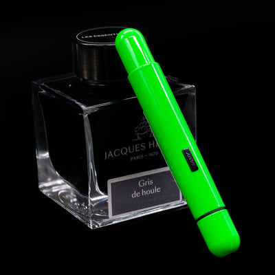 LAMY Pico Ballpoint Pen - Neon Green leaning on a bottle.